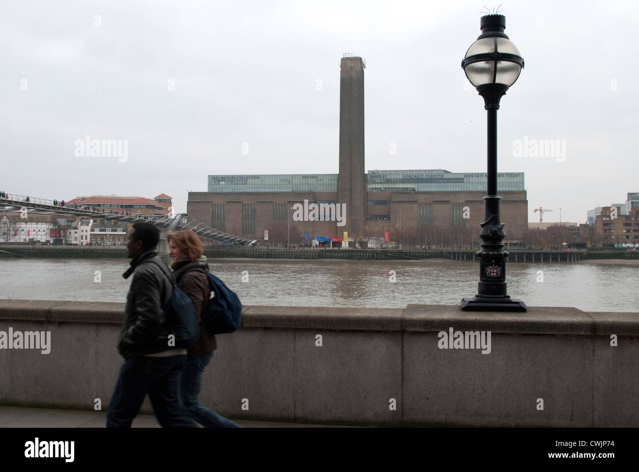 Tate Modern in the Bankside Power Station from the opposite bank of the Thames against a grey sky with a street lamp Stock Photo