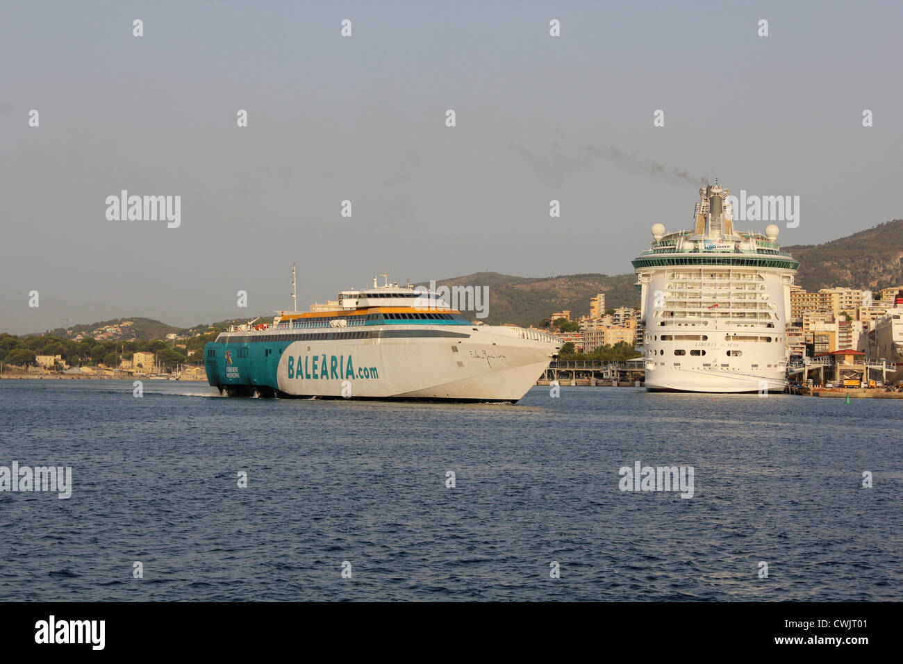 Balearia fast ferry 'Federica garcia Lorca' departing port passing recently arrived Cruise Ship 'Liberty of the Seas' Stock Photo