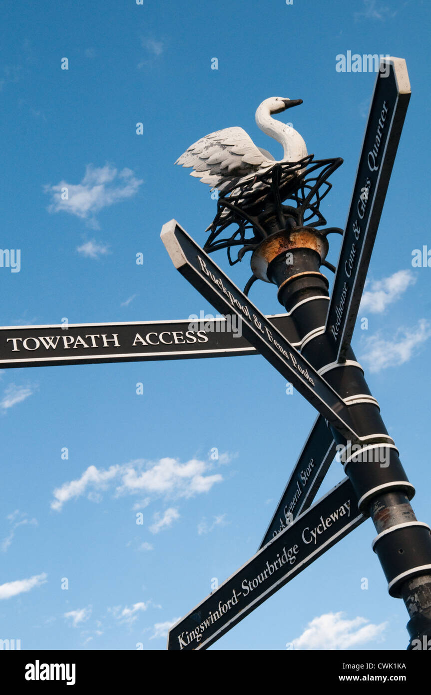 Victorian-style black canal signpost pointing to a towpath in Dudley with a swan on the top of it against a bright blue sky Stock Photo