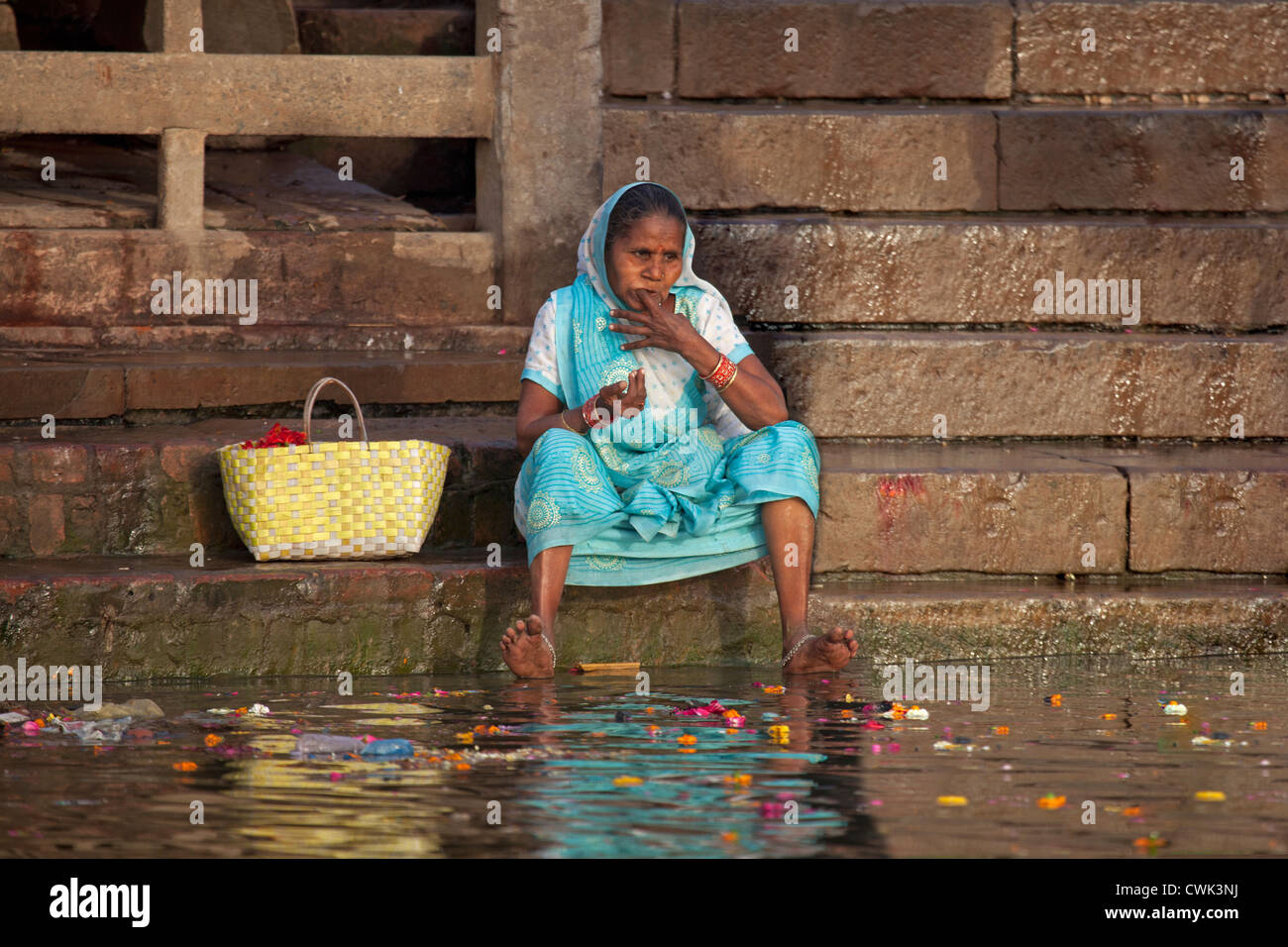 Old Indian woman cleaning her teeth with finger in dirty polluted water of the Ganges river at Varanasi, Uttar Pradesh, India Stock Photo
