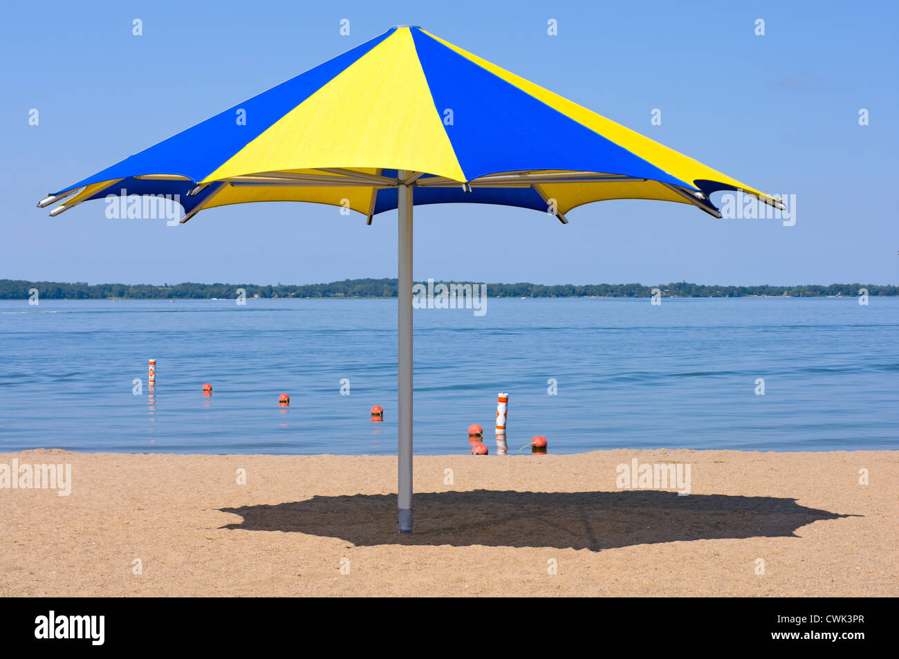 Colorful shade umbrella at sandy beach and shoreline of Lake Waconia Regional Park in Minnesota Stock Photo