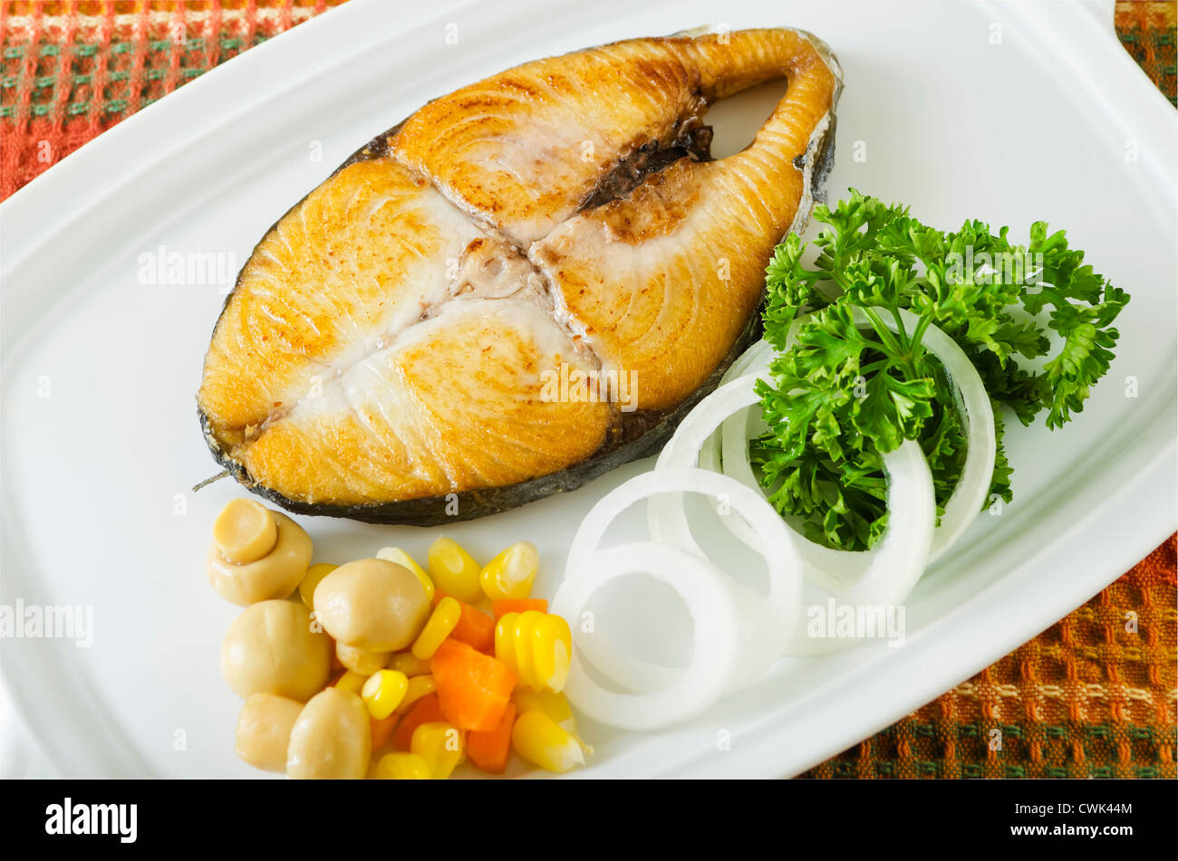 A piece of fried fish with coriander leaves and white onion Stock Photo