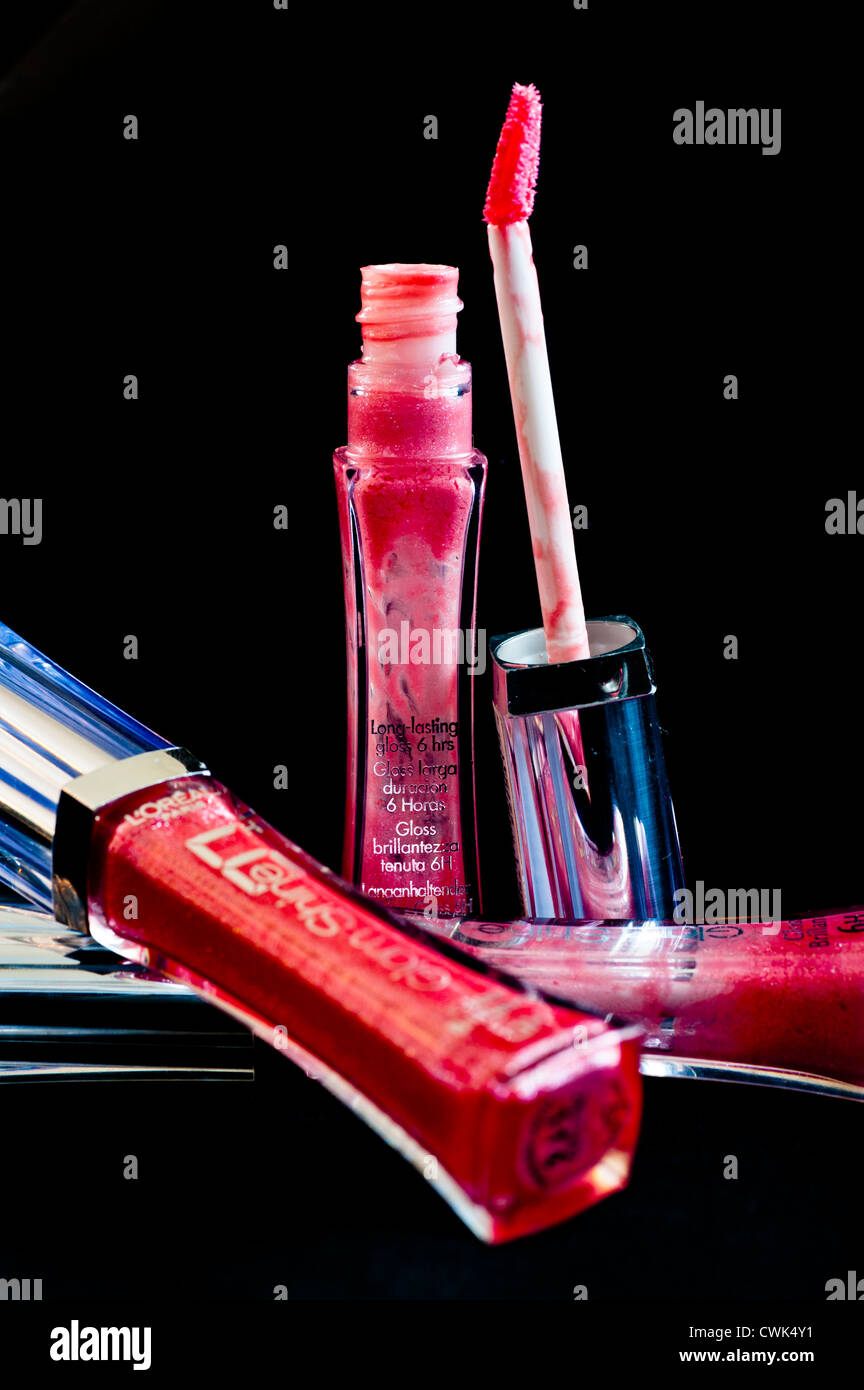 Product photo of lip gloss, with one open bottle and brush and two closed bottles lying on the table Stock Photo