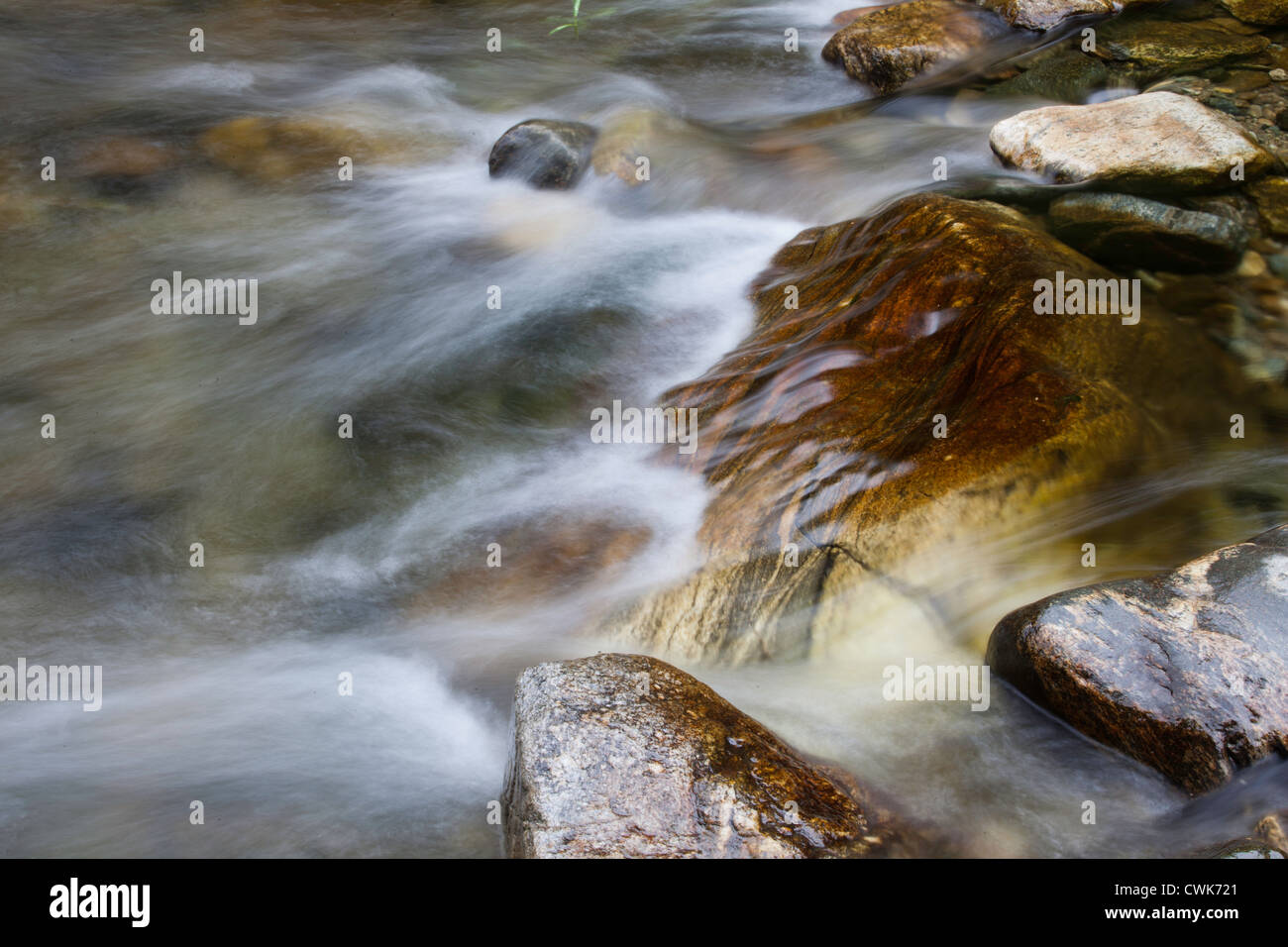 The swift moving water flows along over rocks in this stream Stock