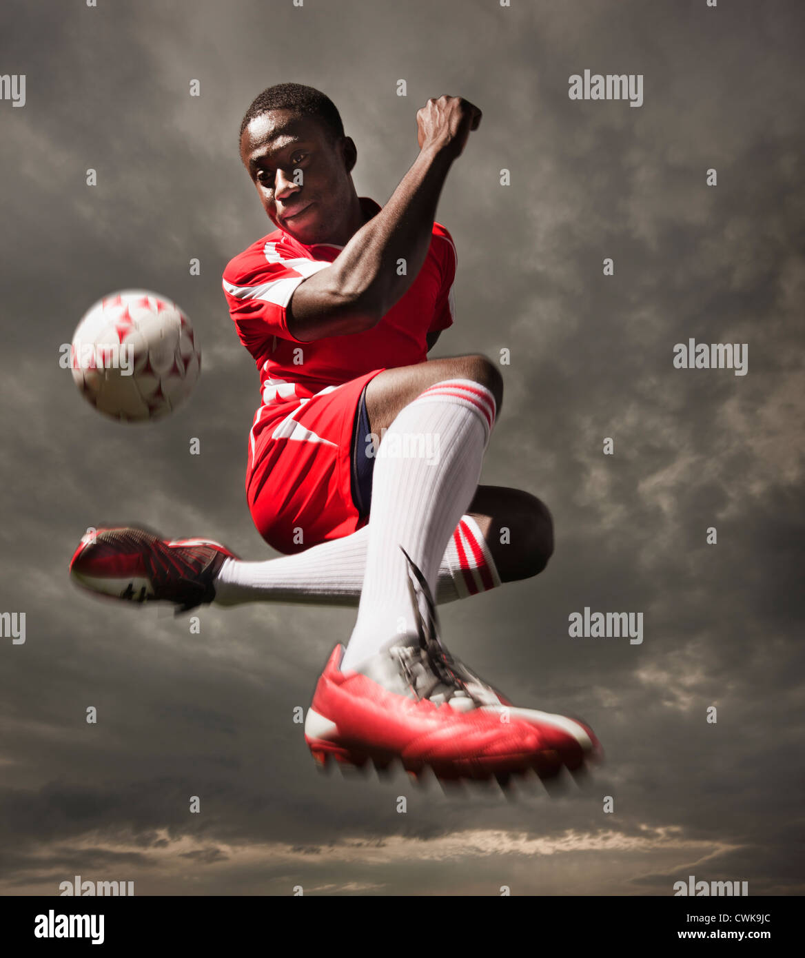 Black soccer player kicking ball Stock Photo