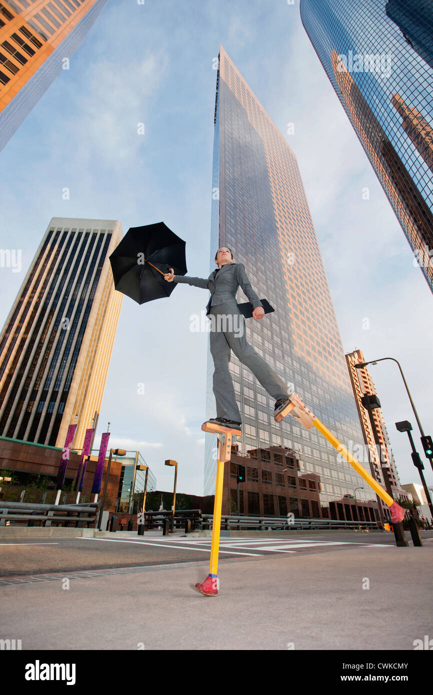 Caucasian businesswoman walking on stilts in urban environment Stock Photo