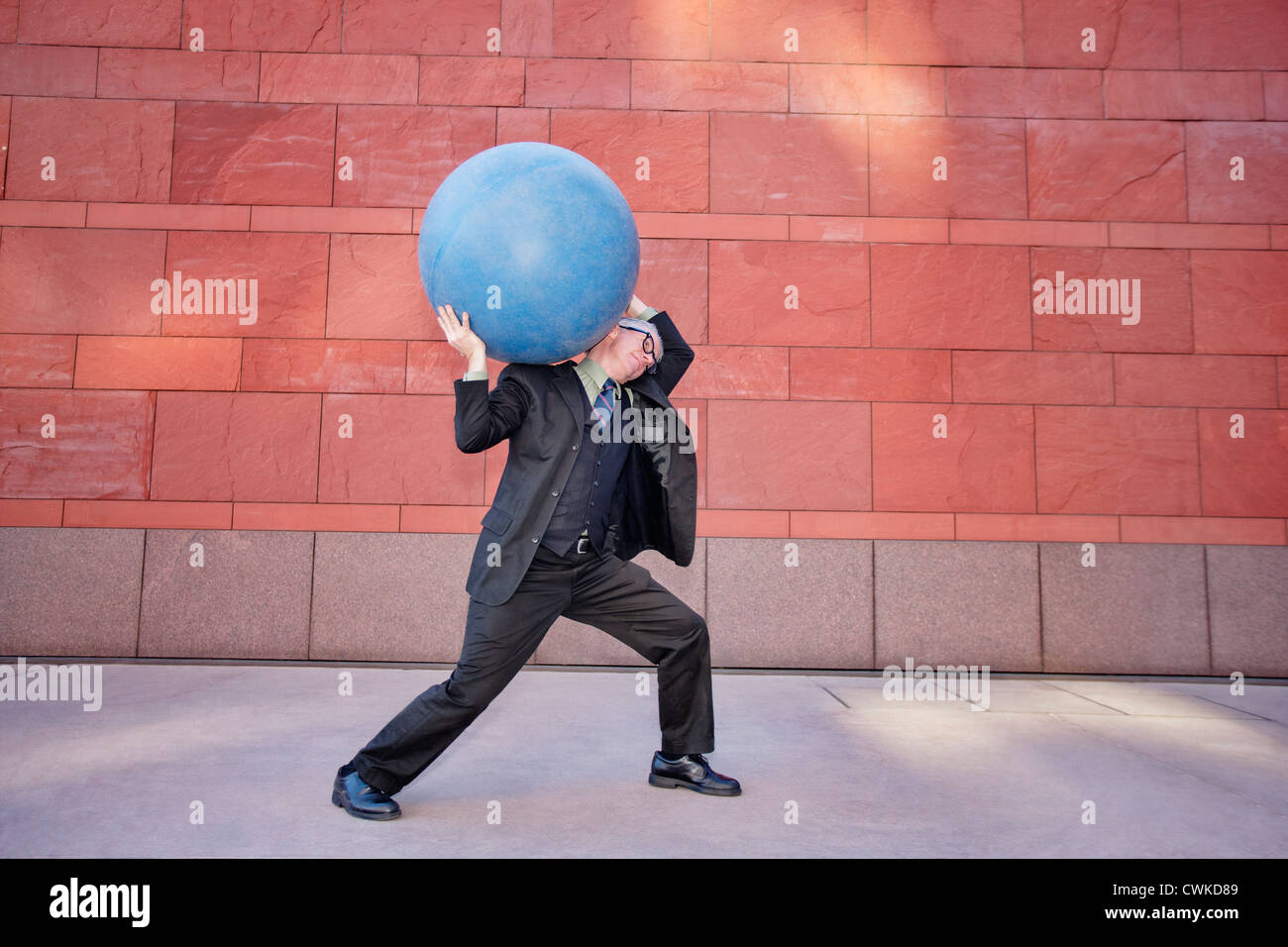 Caucasian businessman carrying heavy ball Stock Photo