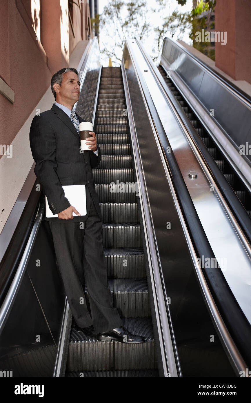 Hispanic businessman on escalator Stock Photo