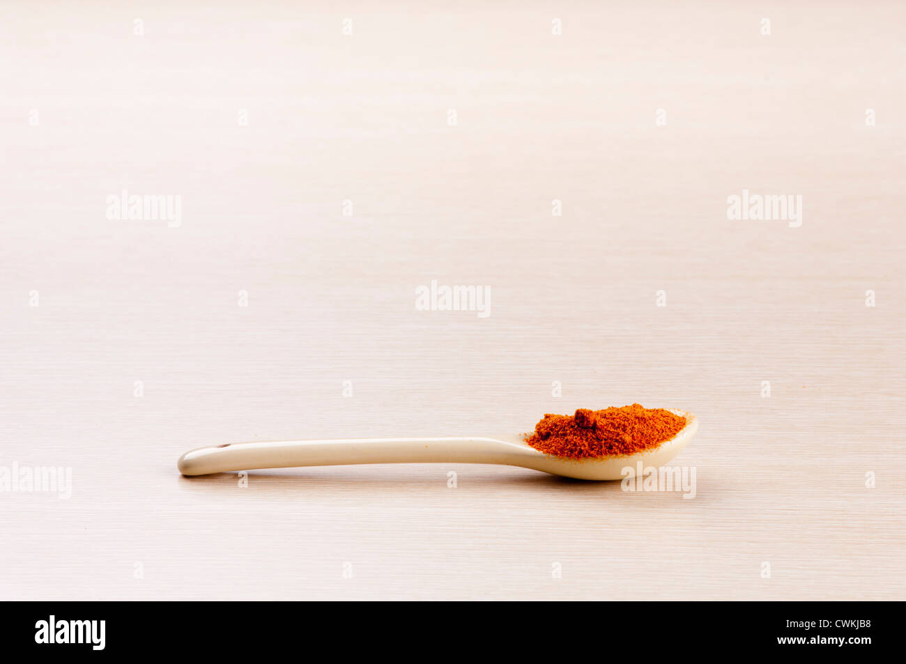 Cayenne Pepper in a spoon over a blured wooden background with copy space Stock Photo