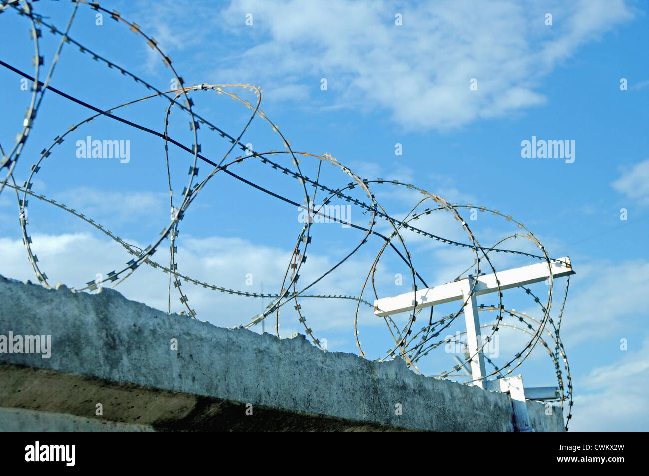 Barbed wire against a blue sky on the wall Stock Photo