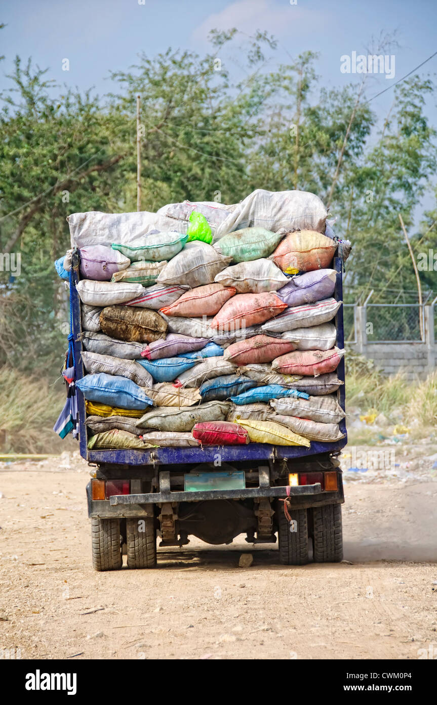 Garbage truck overflowing with trash in old sacks Stock Photo