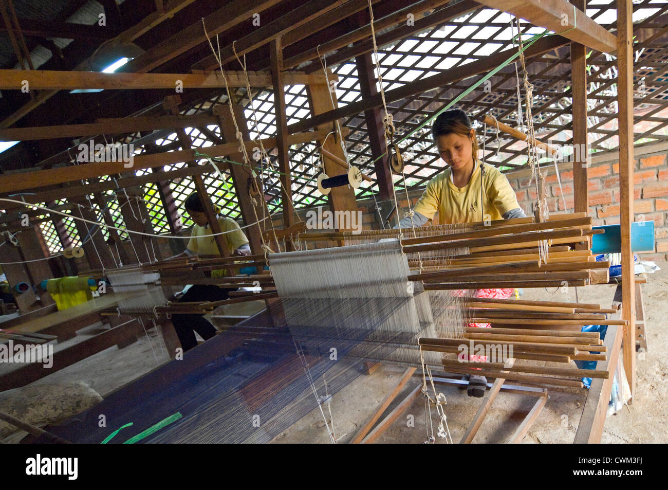 Horizontal close up of women weaving the silk threads into fabric on a