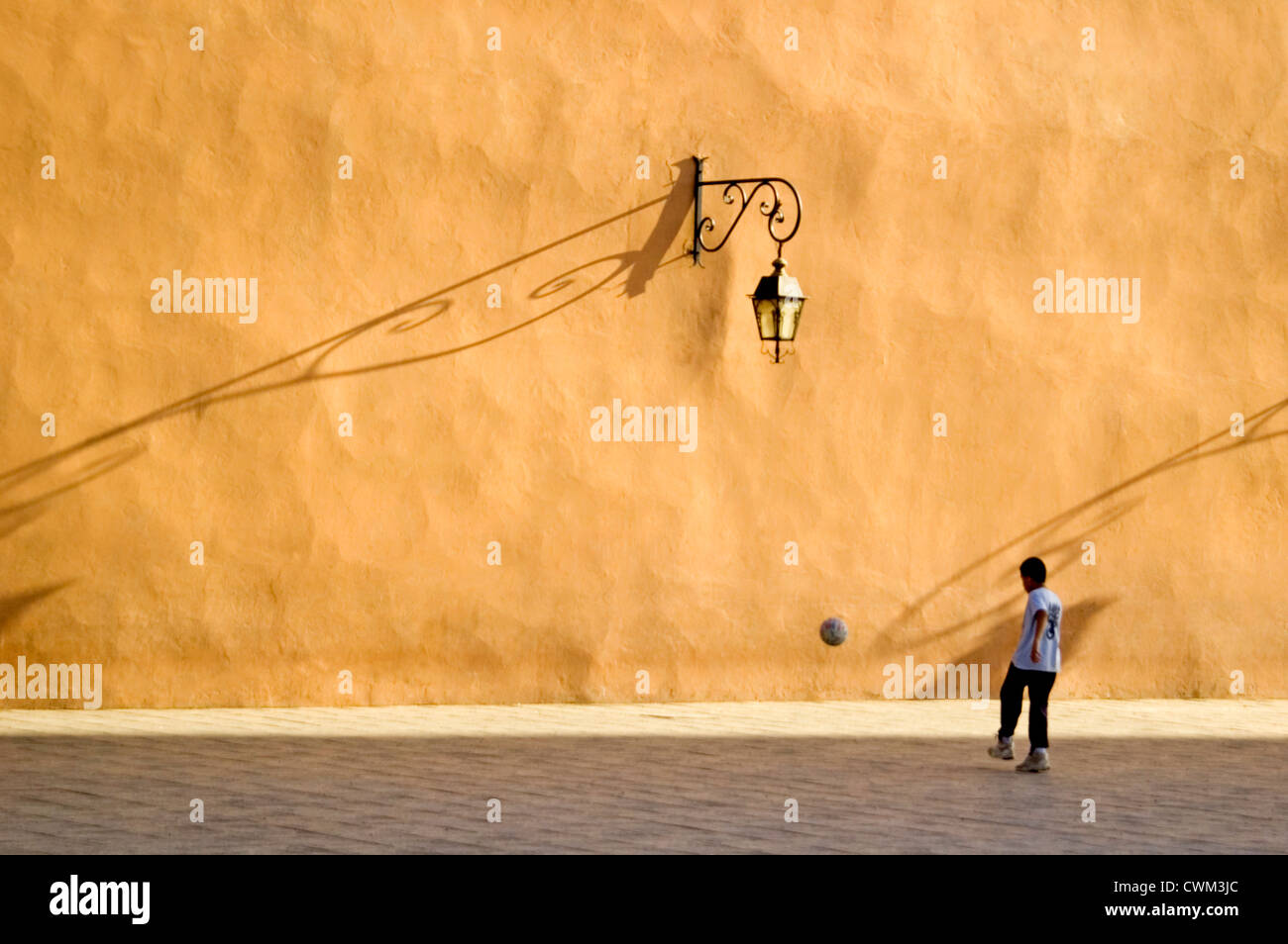 Horizontal portrait of a young Moroccan boy kicking a football against