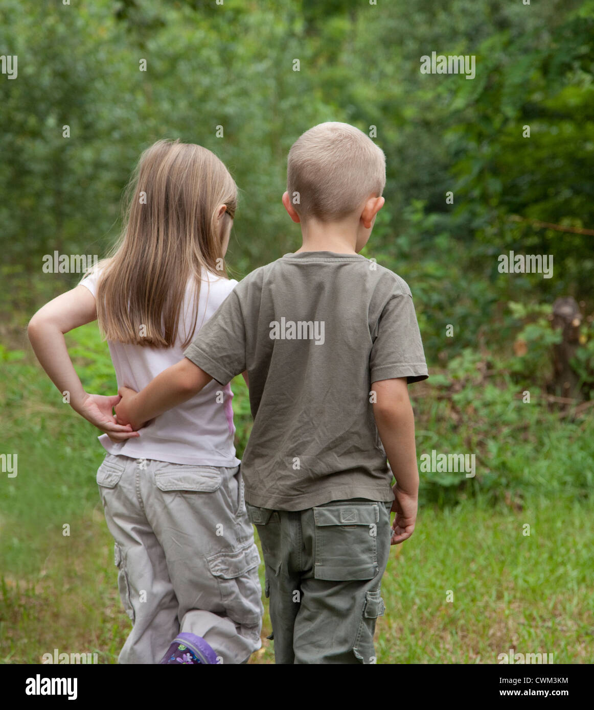 Boy consoling girl with arm around waist walking in field age 8 and 6