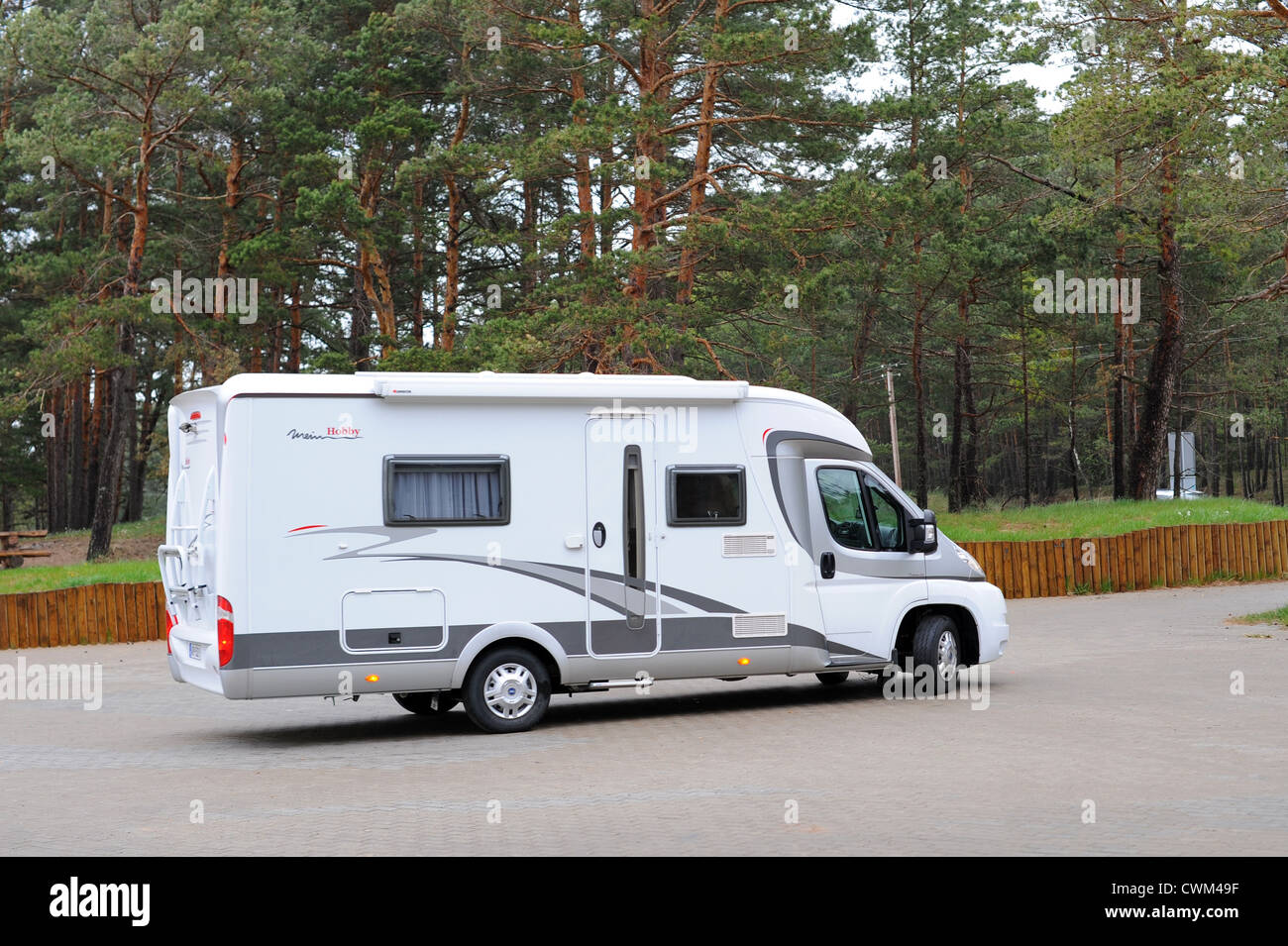 Modern white camping caravan vehicle leaving parking area Stock Photo