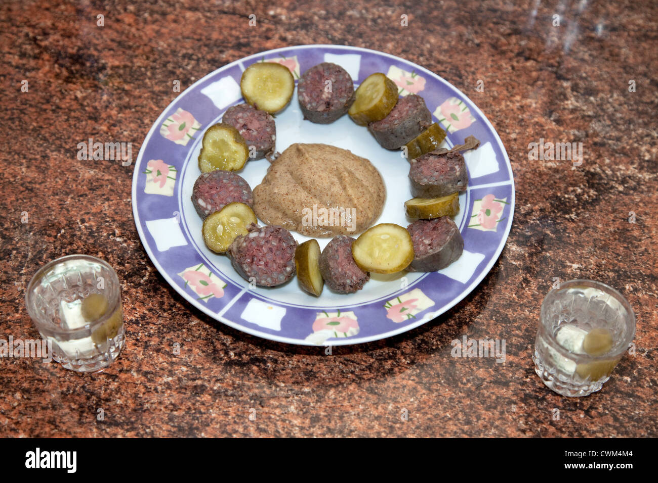 Polish cocktail hour with vodka shots and hors d'oeuvres appetizers of pickles and kielbasa sausage. Zawady Central Poland Stock Photo