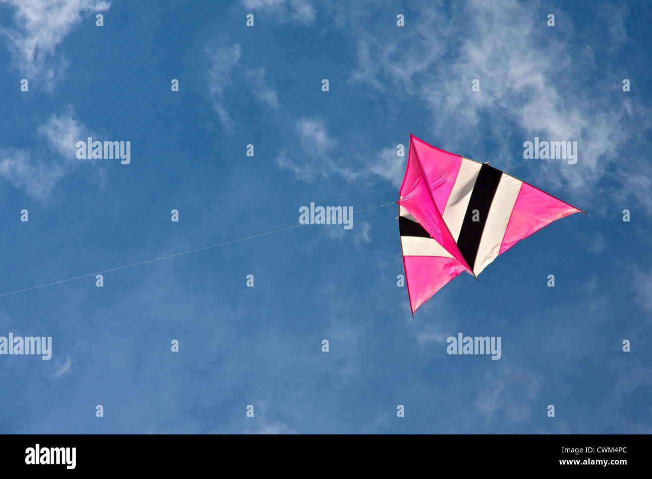Colourful kite flying against blue cloudy sky Stock Photo