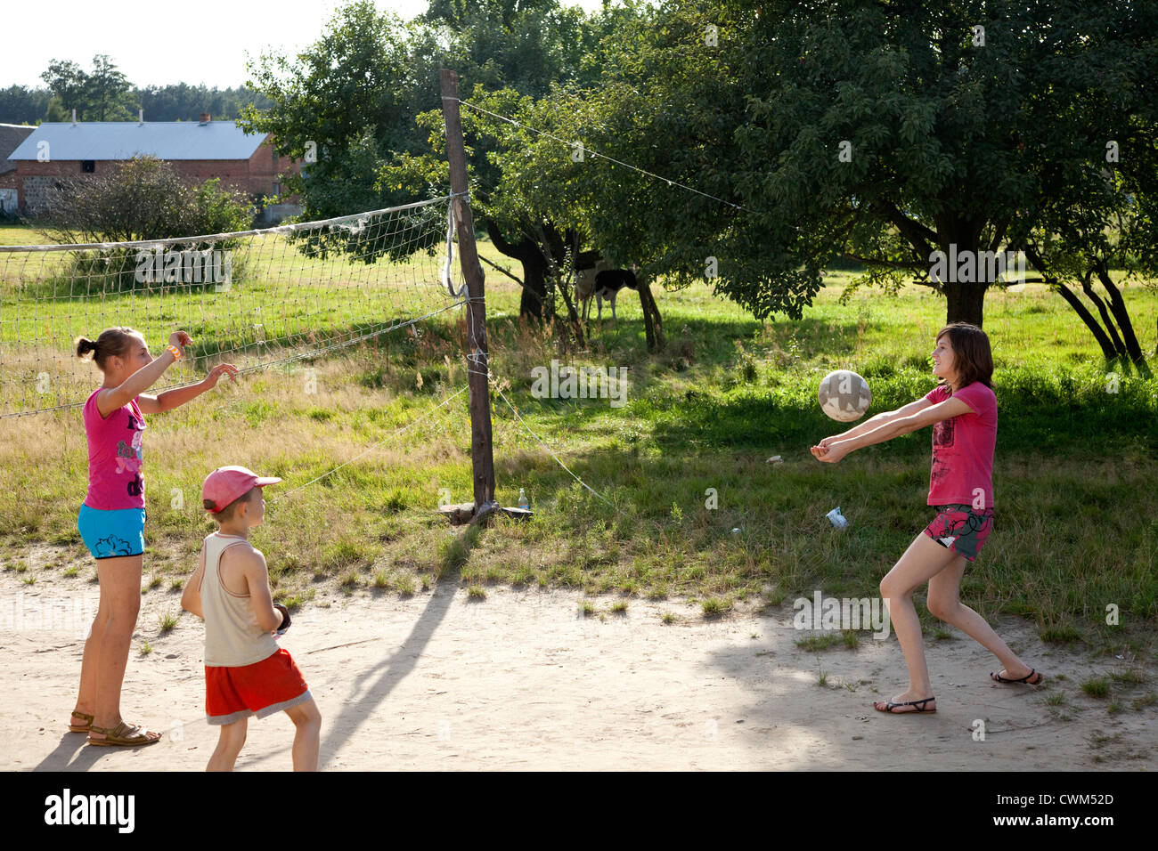 Teens and children playing volleyball in village sandlot course. Mala Wola Central Poland Stock Photo