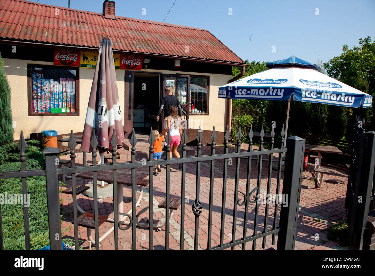 Small Polish convenience grocery store patio with umbrellas and tables. Krolowa Wola Central Poland Stock Photo