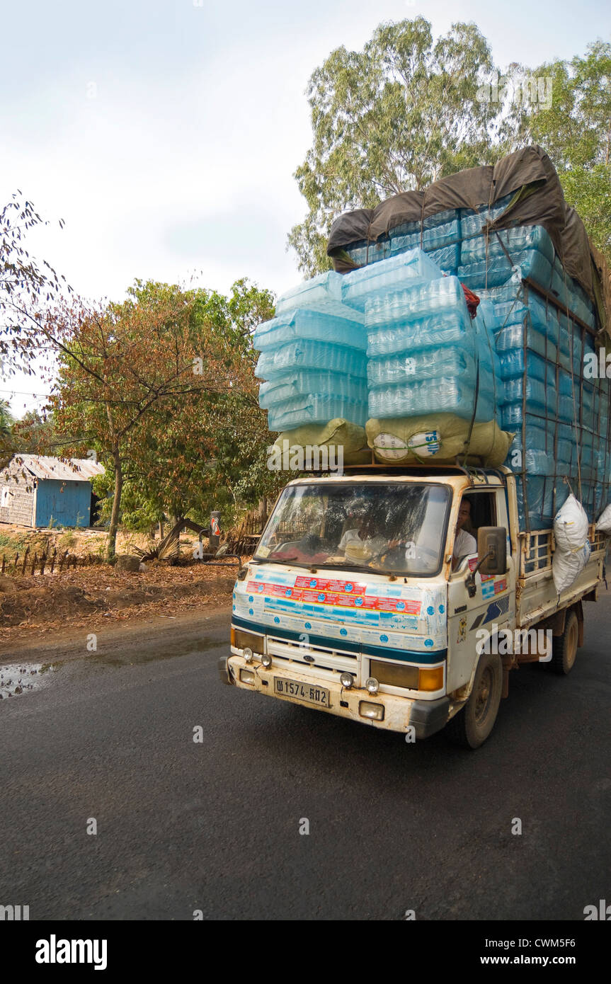 Vertical wide angle view of a lorry overloaded with plastic water bottles driving passed in Cambodia. Stock Photo