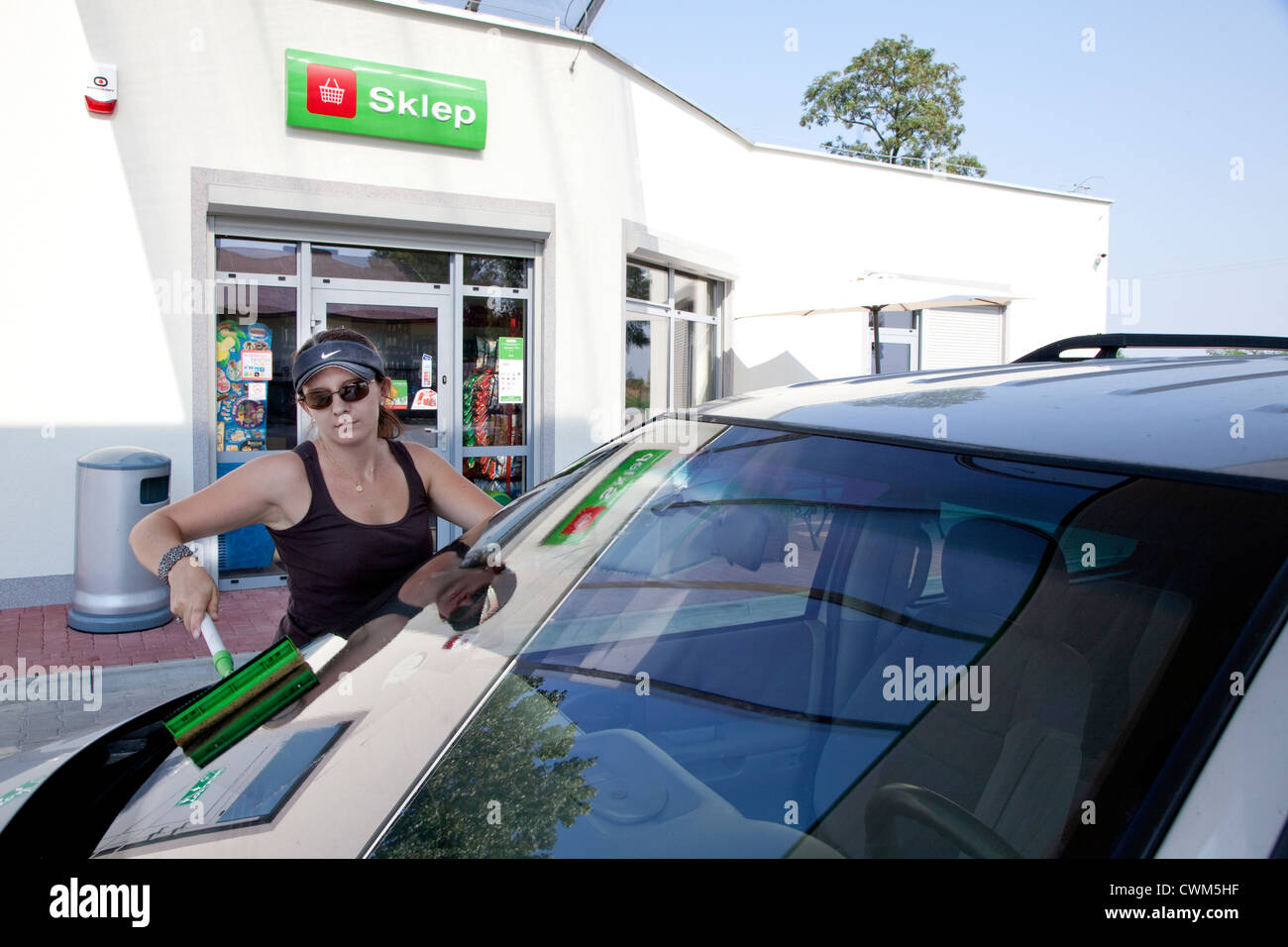 Polish woman age 32 washing automobile windshield at a quick stop convenience store petrol station. Rzeczyca Central Poland Stock Photo