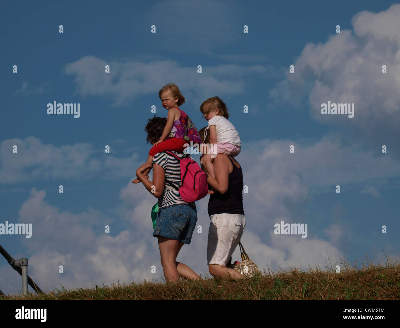 Couple carrying children on their shoulders, UK Stock Photo