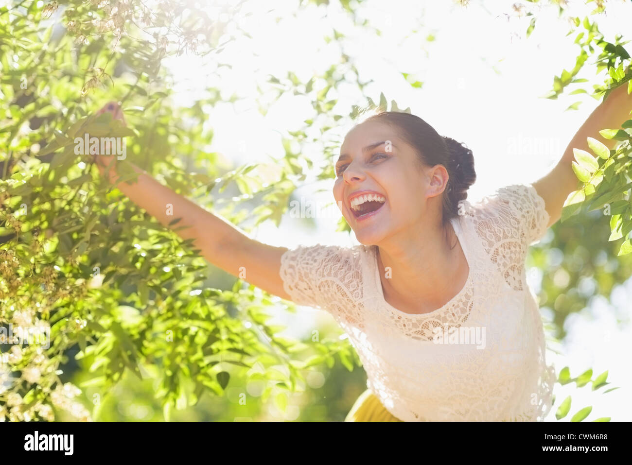 Cheerful young woman playing in foliage in forest Stock Photo