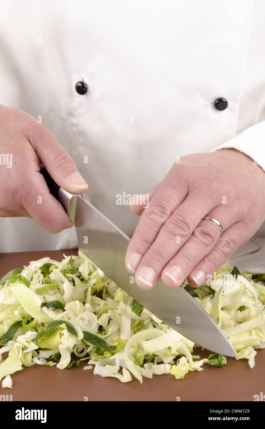 female chef cuts fresh cabbage with a large knife Stock Photo
