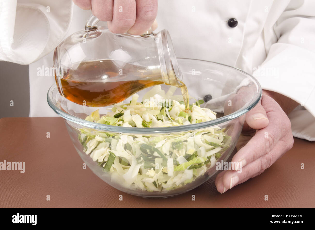 female chef fills some sunflower oil into a salad Stock Photo