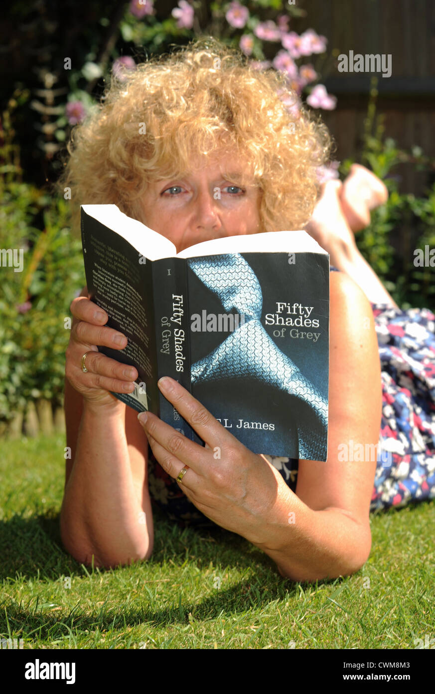 Mature woman in 50s reading sexy erotic novel Fifty shades of Grey by E L  James while sitting in her garden UK 2012 Stock Photo - Alamy