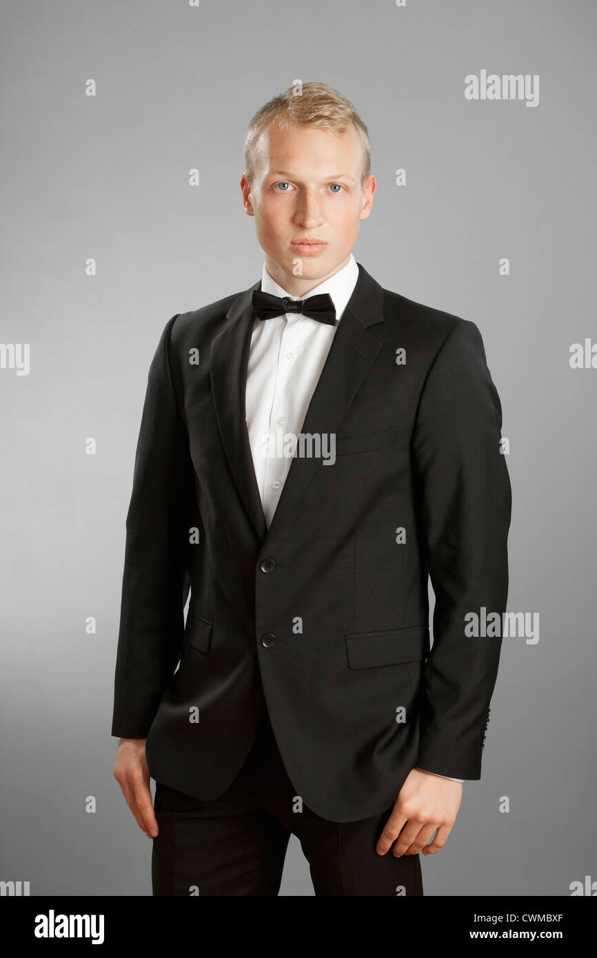 Young man in black suit against gray background Stock Photo - Alamy