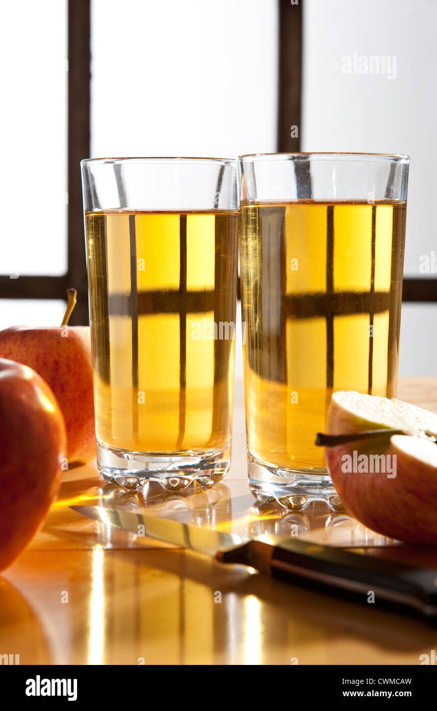 Apple juice -Two glasses of apple juice on a kitchen table, with apples Stock Photo