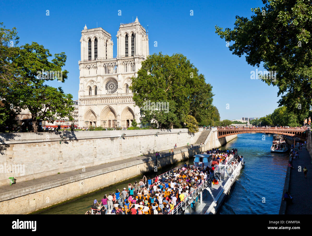 Front facade of the cathedral of Notre Dame with a tour boat passing on the River Seine Ille de la Cite Paris France EU Europe Stock Photo