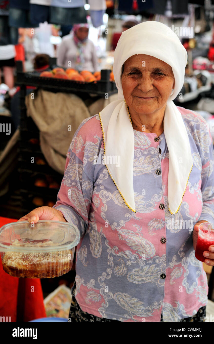 Upright view of elderly Turkish woman wearing headscarf holding honeycomb for sale in market near Dalyan Turkey Stock Photo