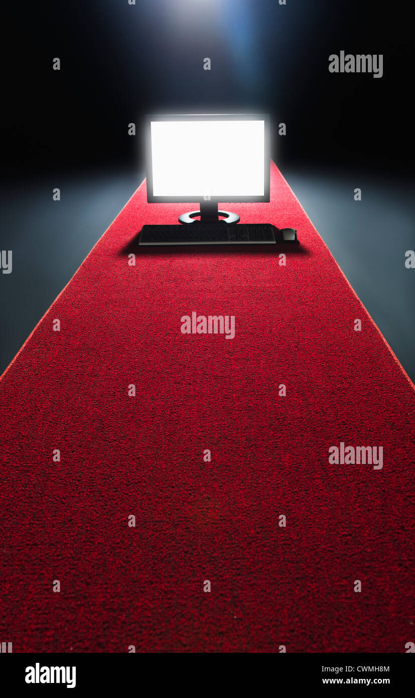 Studio shot of glowing computer on red carpet Stock Photo