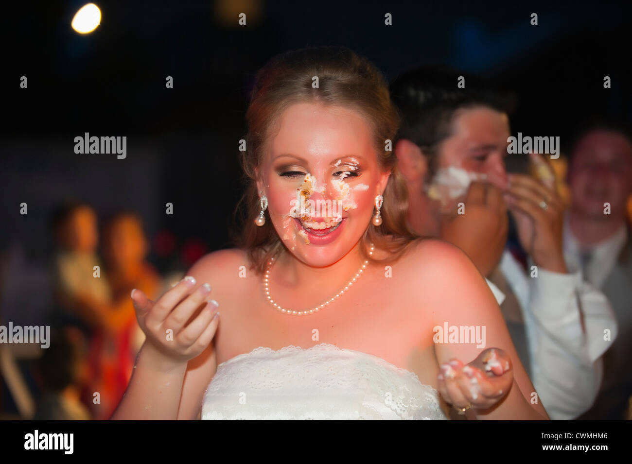 Bride and groom smearing each others faces with icing during a