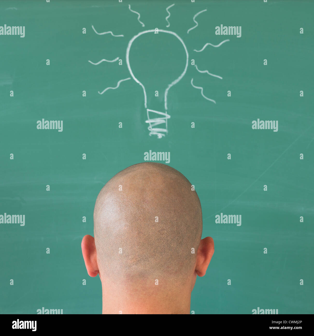 Man in front of blackboard with drawing depicting Lightbulb Stock Photo