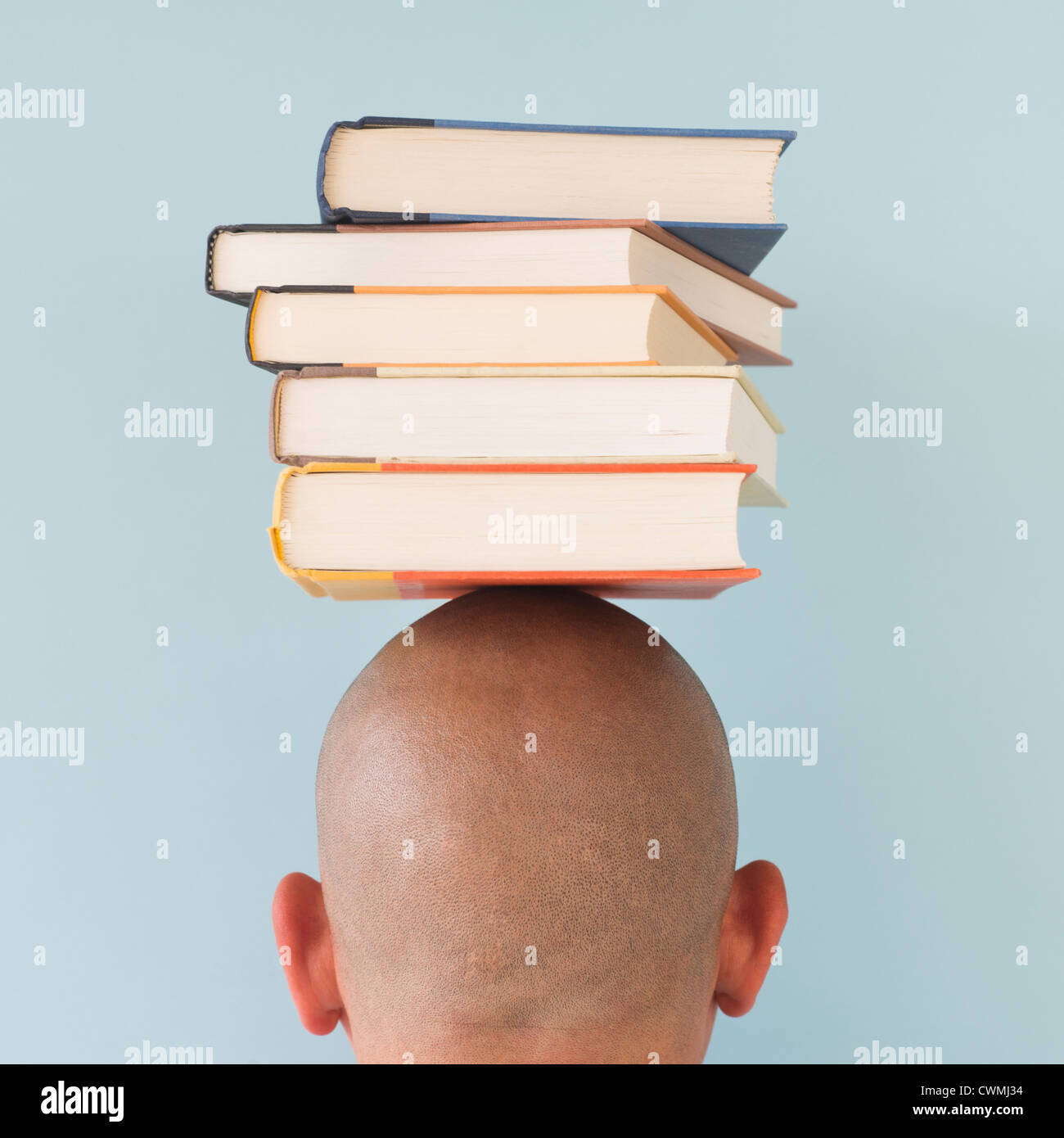 Studio shot of man with stack of books on head Stock Photo