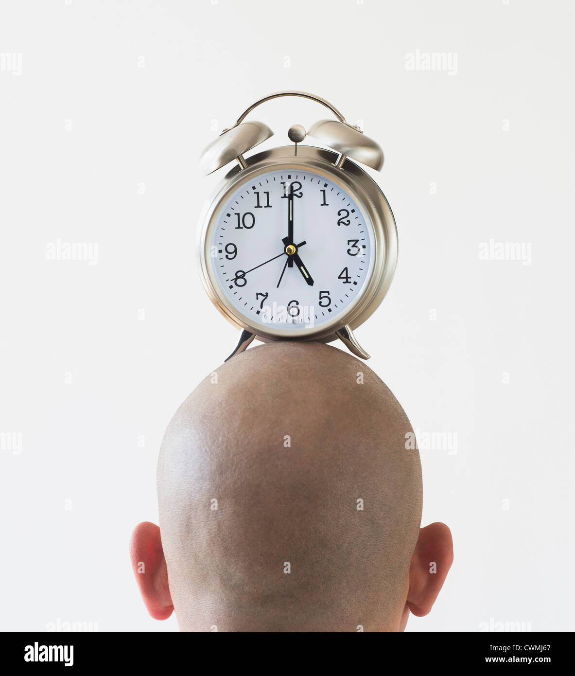Back view of man with alarm clock on shaved head Stock Photo