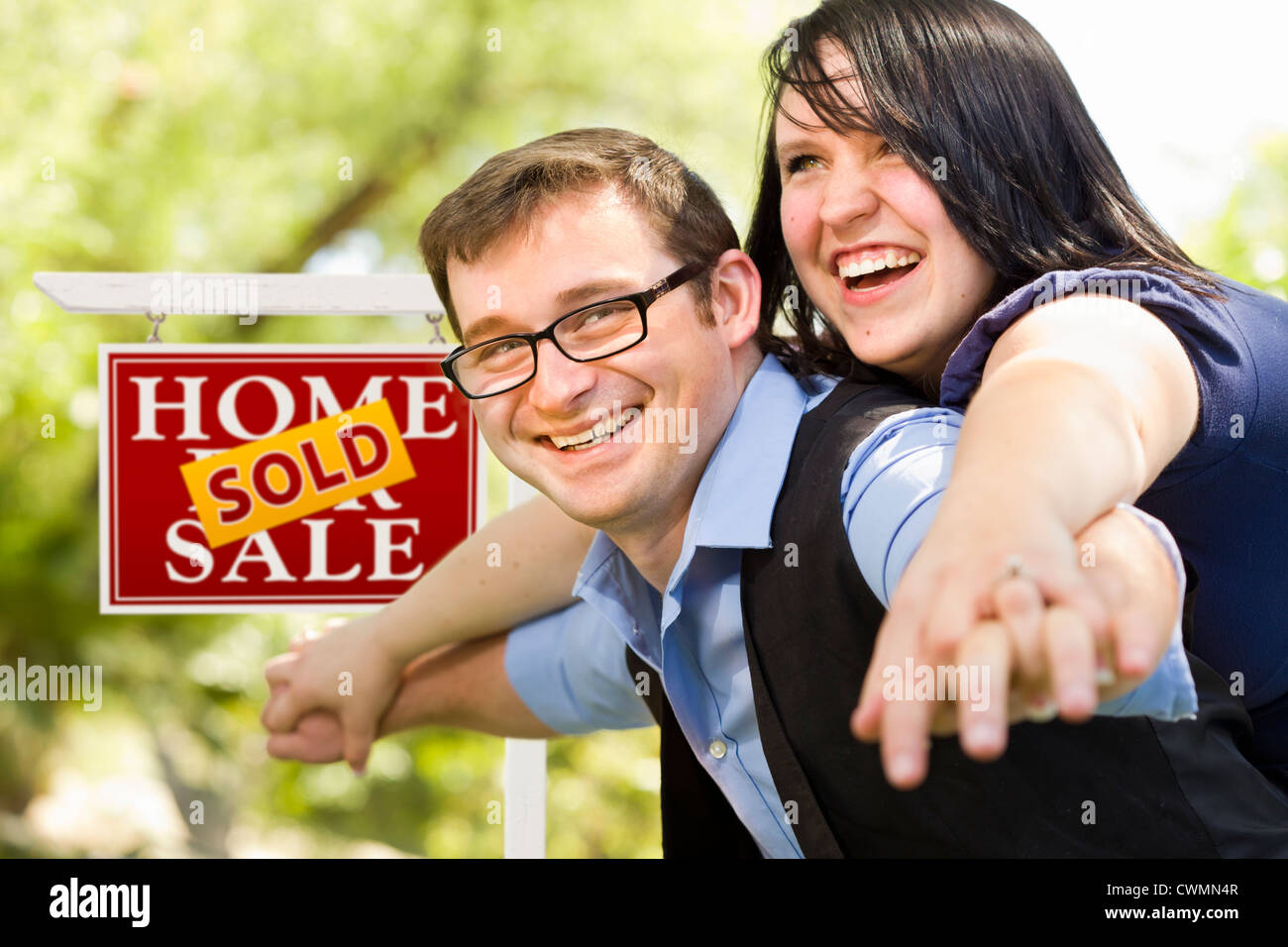 Happy Attractive Caucasian Couple in Front of Sold Real Estate Sign ...