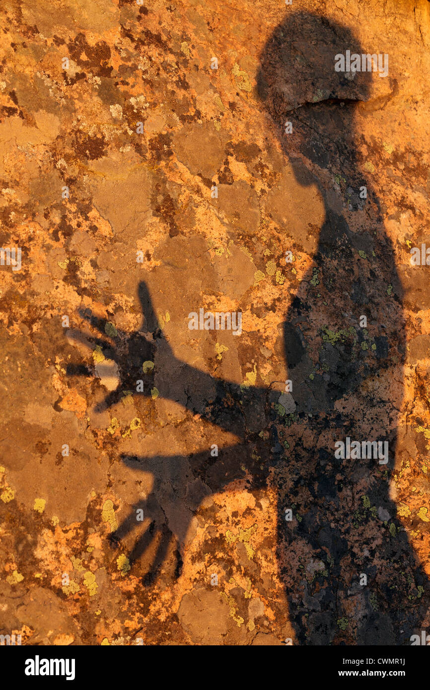 textured woman shadow on granite rock under warm sunset light Stock Photo