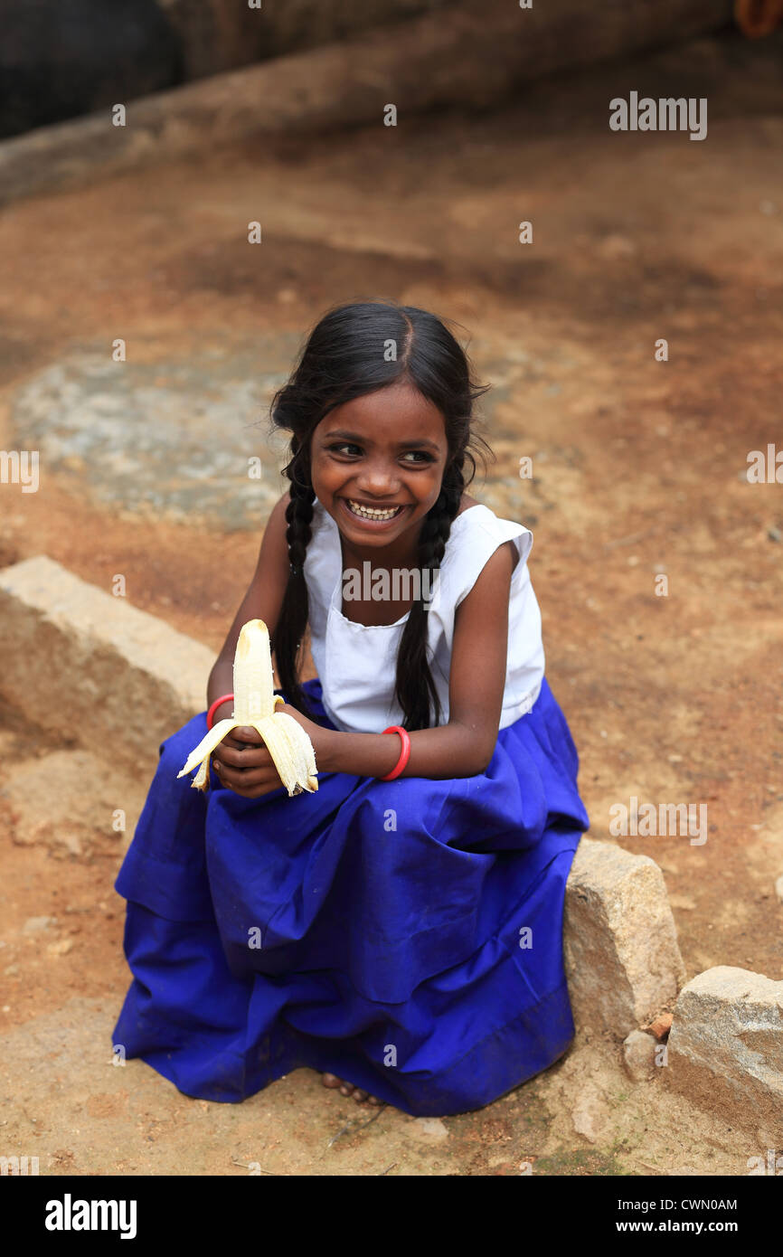 Young Indian rural girl eating a banana Andhra Pradesh South India ...