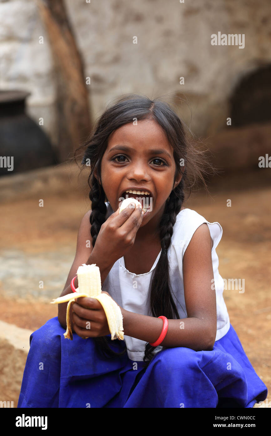 Young Indian rural girl eating a banana Andhra Pradesh South India ...