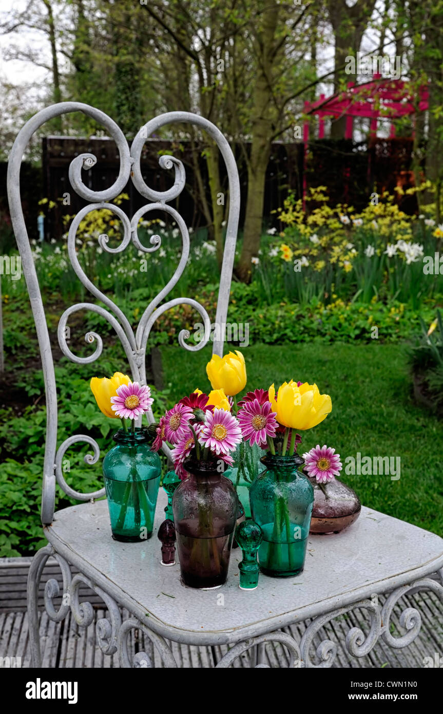 gerbera tulips ornate glass vase vases ornamental chair metal frame garden design feature gardening Stock Photo
