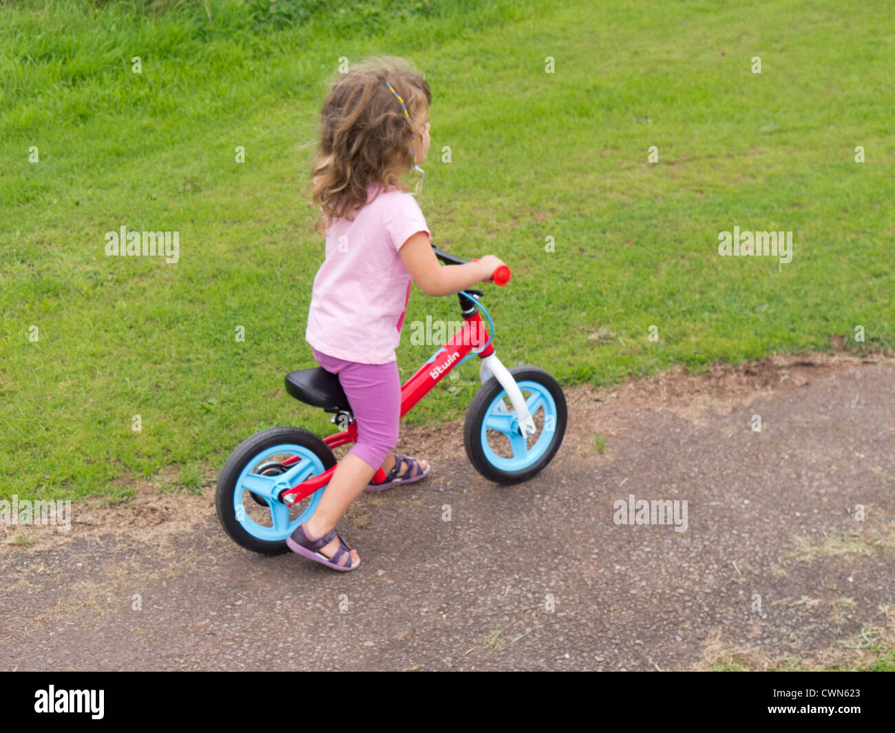 Young child using a balance bike to learn to ride a bicycle Stock Photo