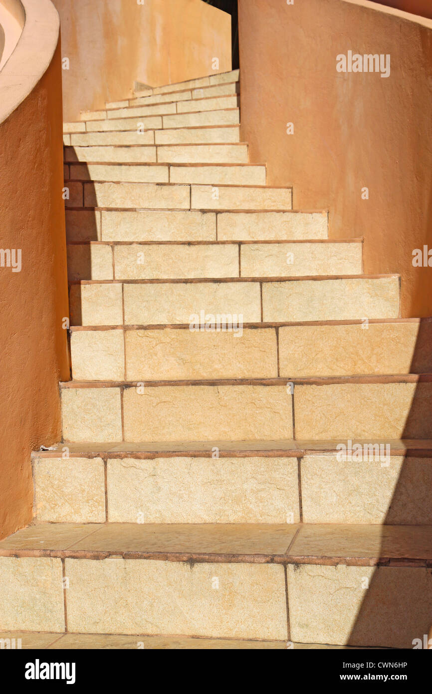 Warm beige stones wind upwards towards the top of a staircase in Belize City, central America Stock Photo