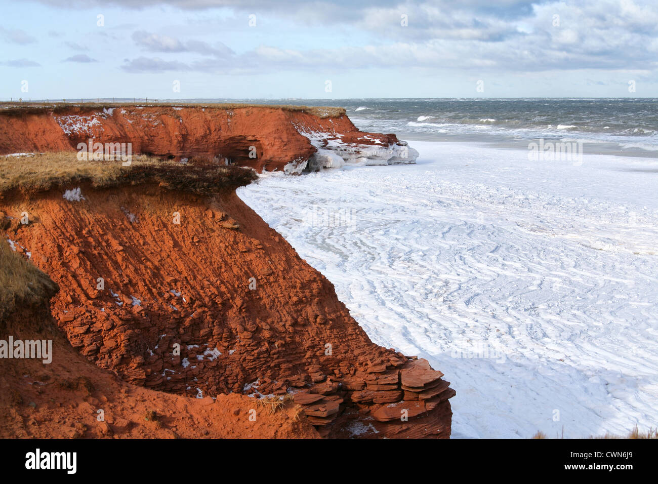 Red sandstone cliffs and moving ice flows in the ocean on the north shore of Prince Edward Island, Canada in winter. Stock Photo