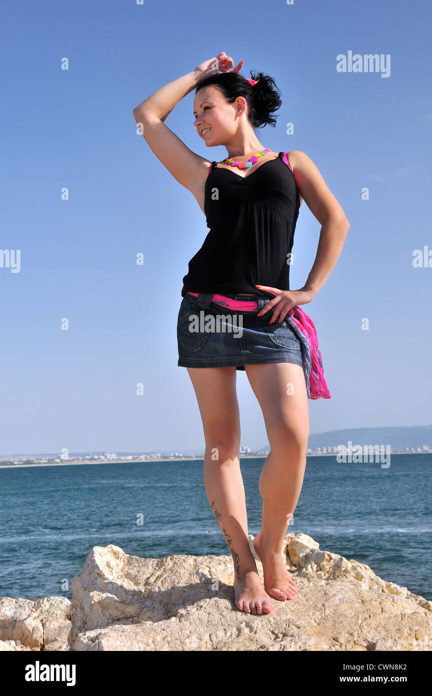Young girl dancing barefoot on a rock on the shore of the Mediterranean