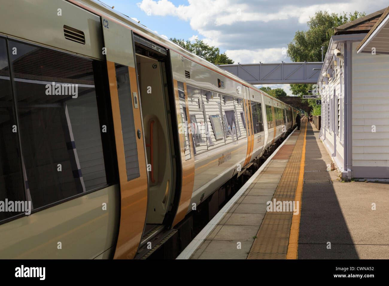 SouthEastern train with doors open stopped by platform at railway station on London to Ashford line at Pluckley Kent England UK Stock Photo