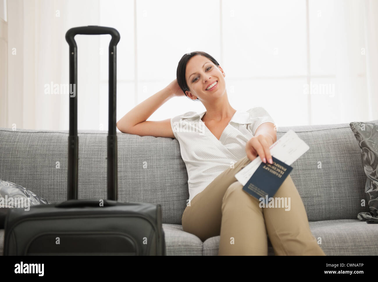 Smiling young woman with bag holding passport and air ticket Stock Photo